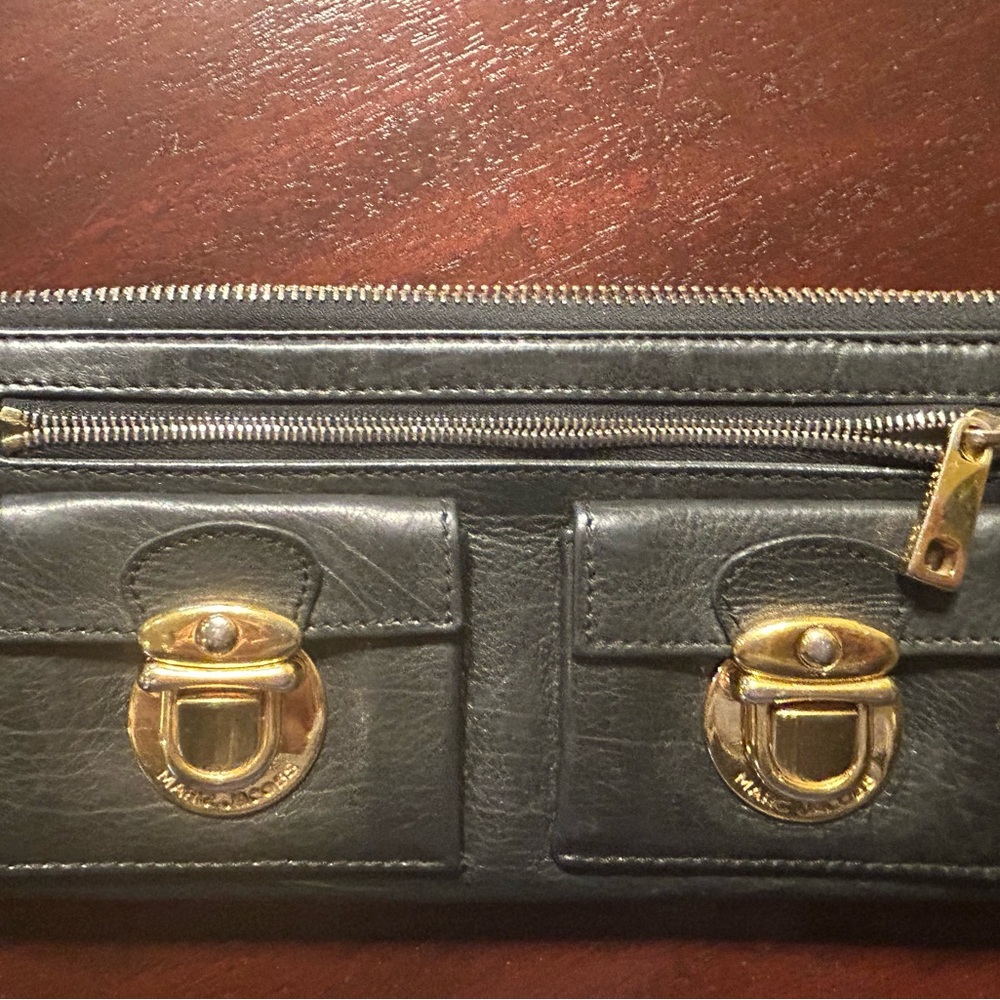 Marc Jacobs black leather wallet with brass decorative tab pockets.